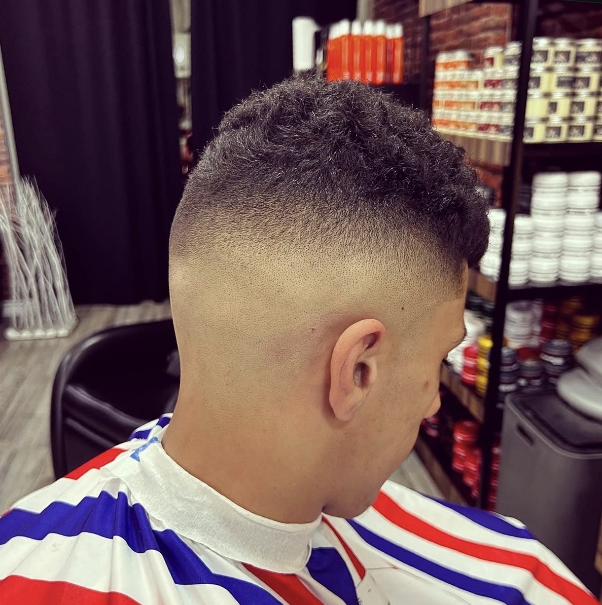 Skin fade met een gestreepte kapmantel in rood, wit en blauw